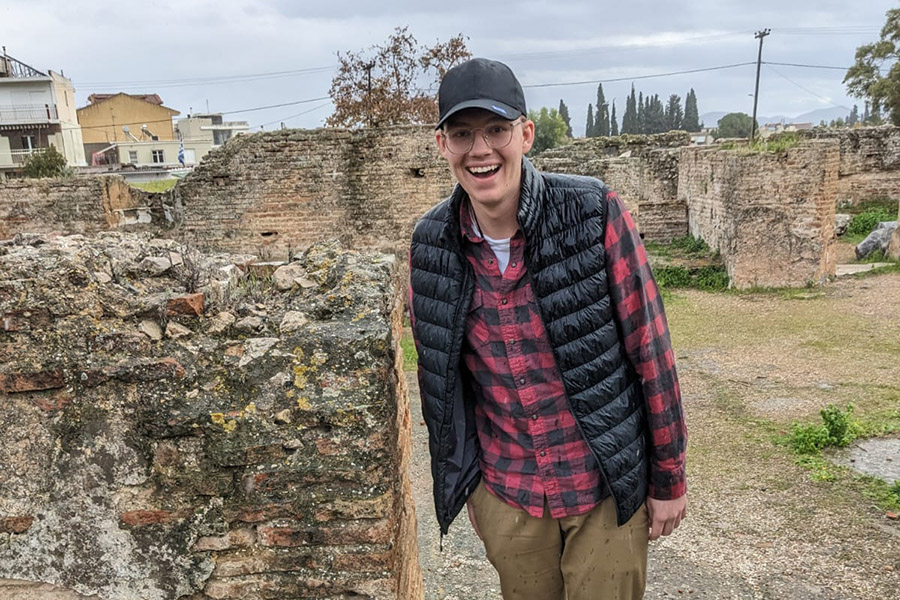Student Timothy Dueck standing next to Greek ruins.