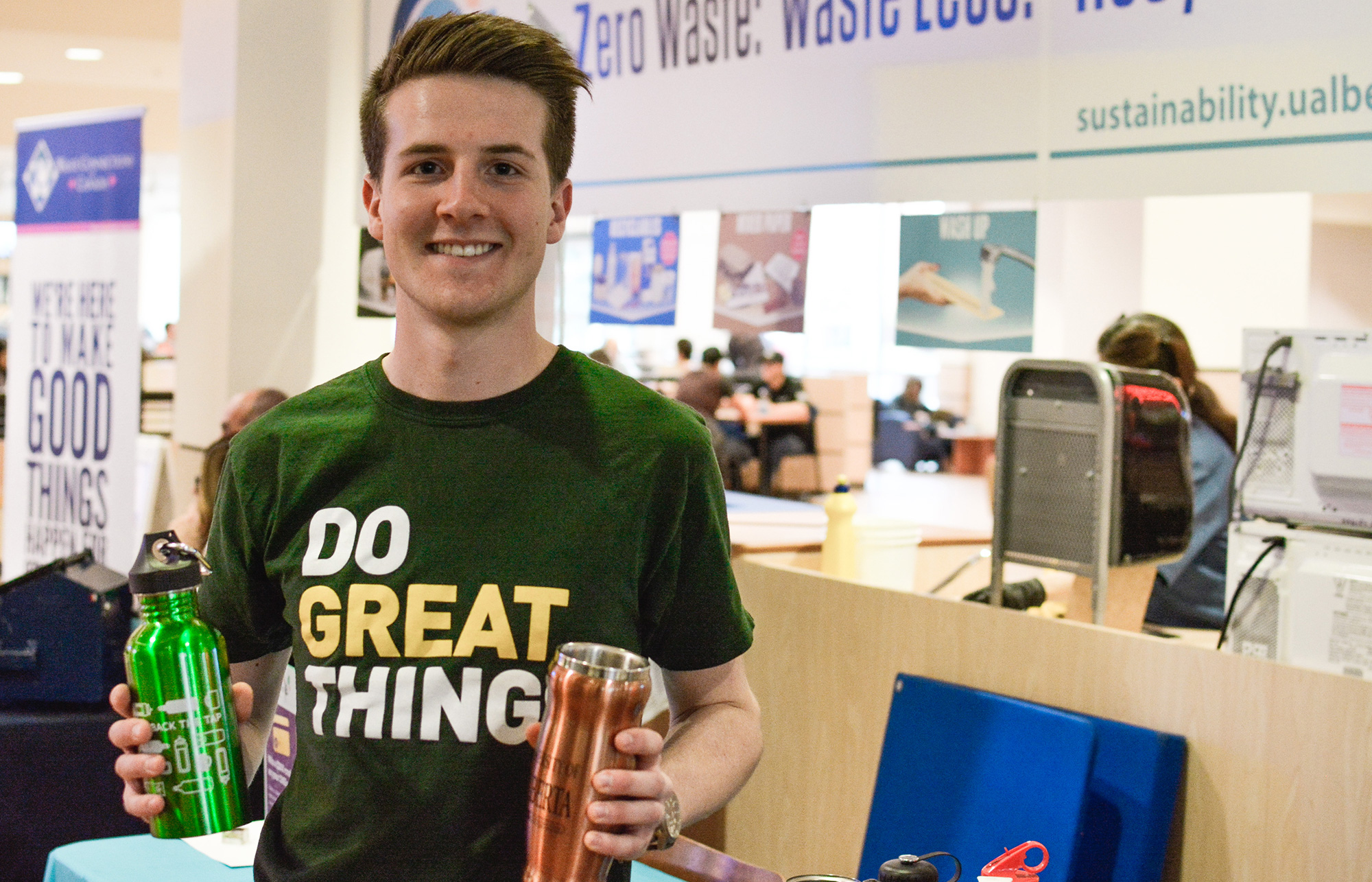 Student volunteer holding Sustainability Council merchandise and smiling at the camera