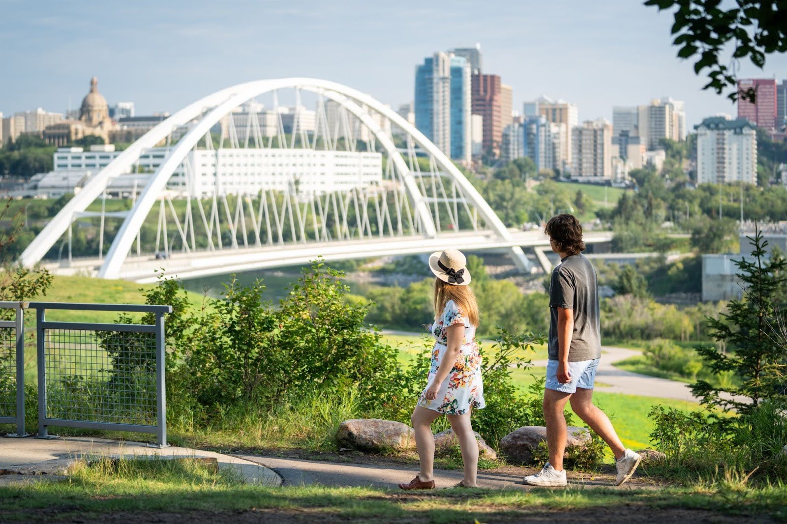 Two people walking along Saskatchewan drive looking at Edmonton's low-level bridge in summertime