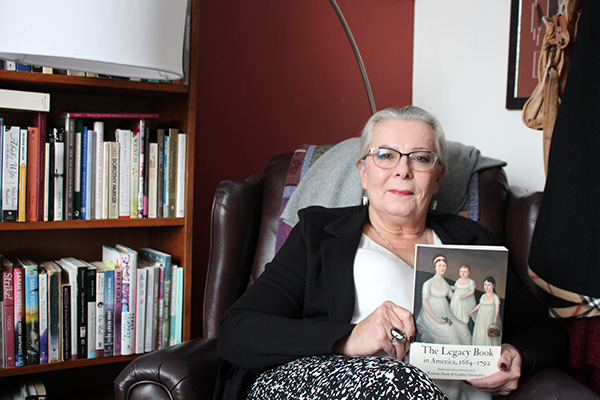 A photo of Dr. Harde sitting in front of a bookcase holding her new book.