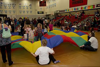 A photo of children and volunteers playing with a parachute