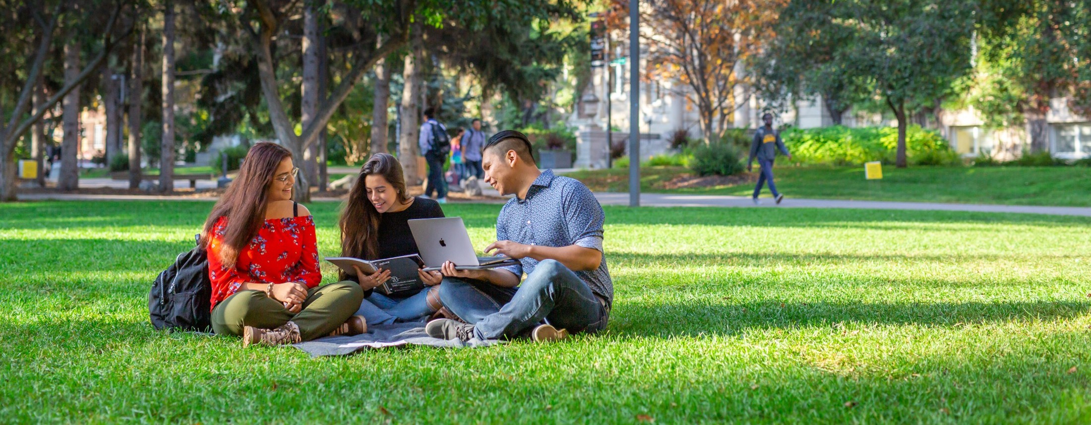 Three students sitting outside in the Quad