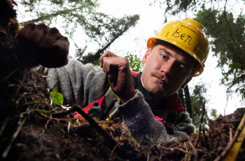 A photo of Ben Strelkov working in the dirt with a yellow hard hat on.