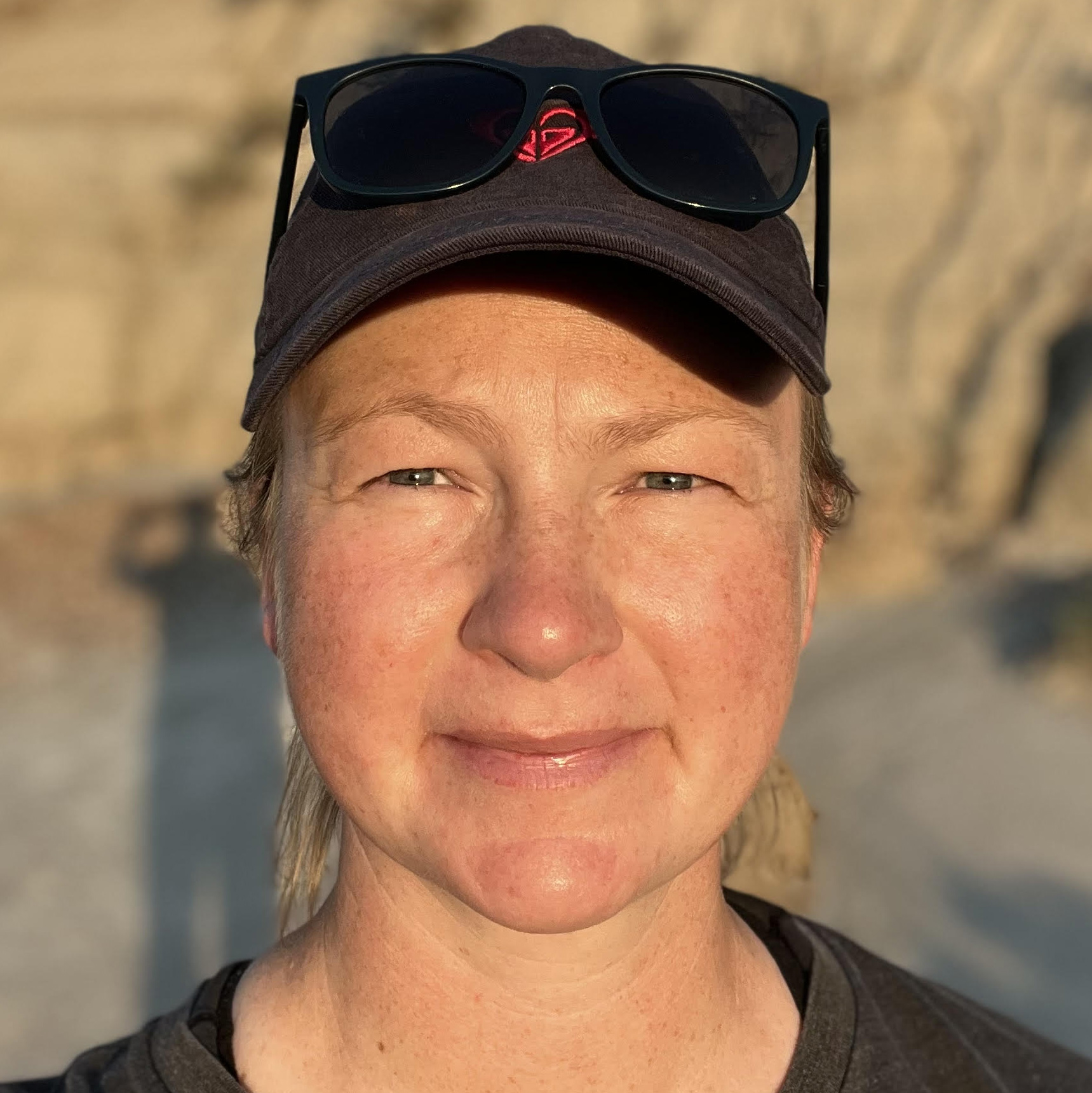 headshot of Christina posting in a mountain landscape