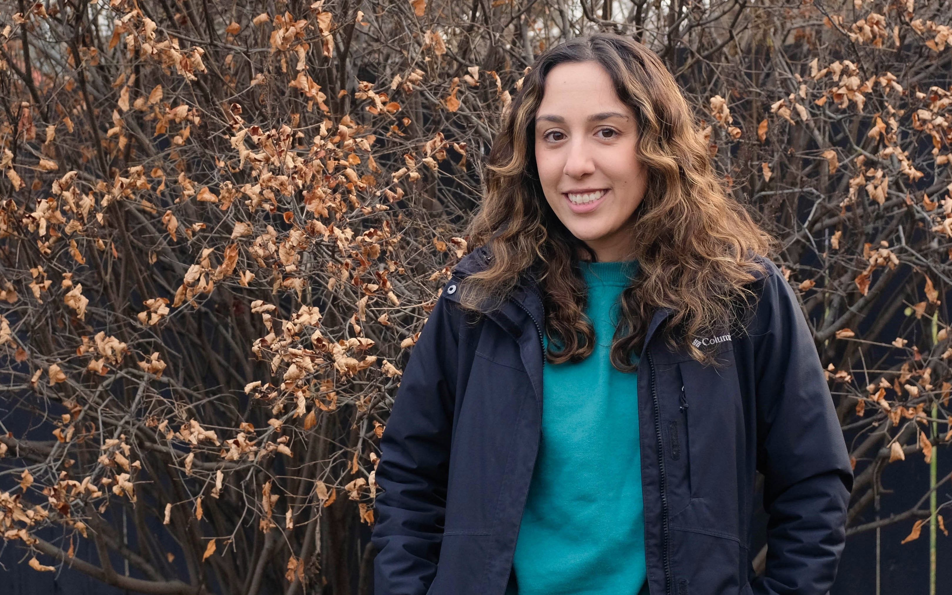 Fall portrait of Marina standing in front of some trees.