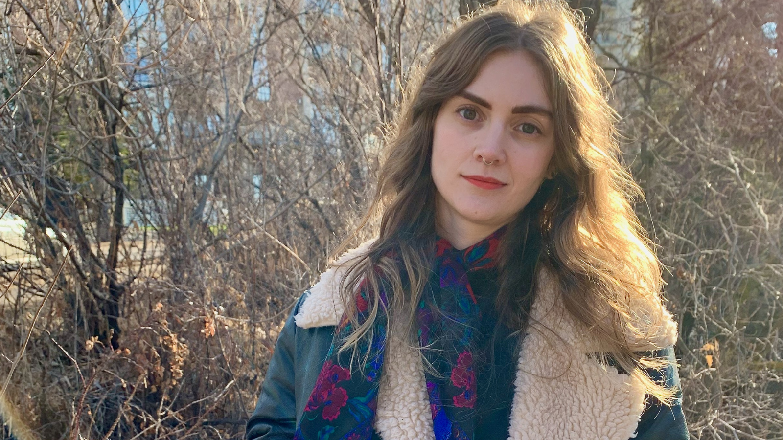 Portrait of Zoe in front of trees, in the fall.