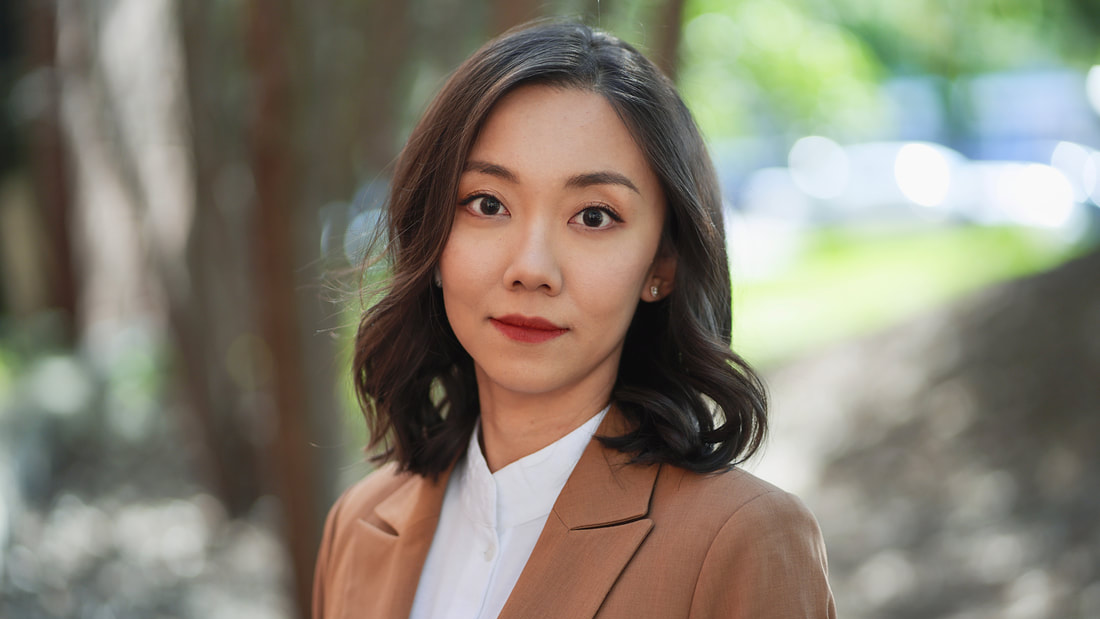 dan yu poses in front of a green treed landscape