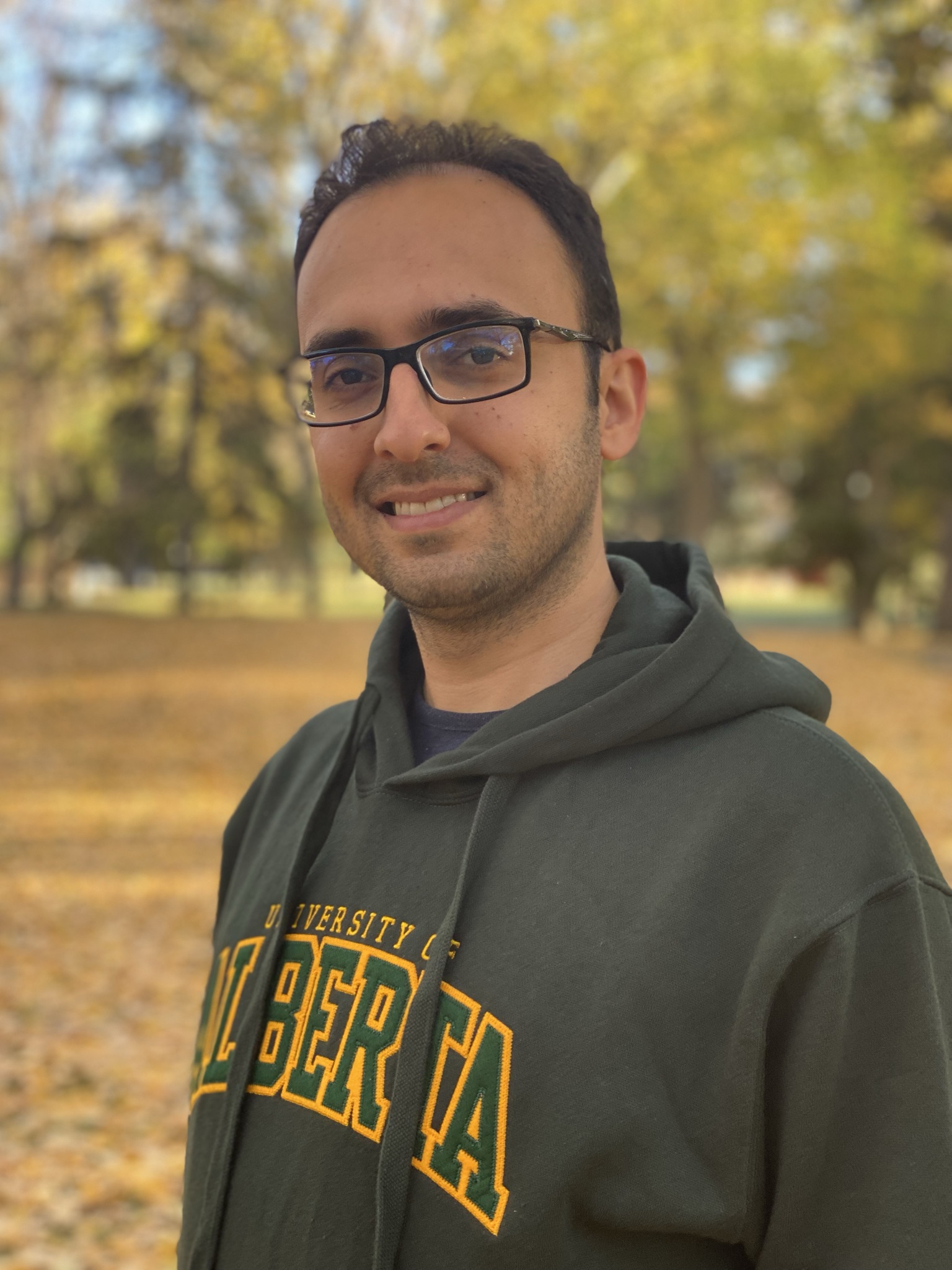 Photo of Emad Yuzbashian poses outside on a sunshiny fall day wearing a U of A sweater