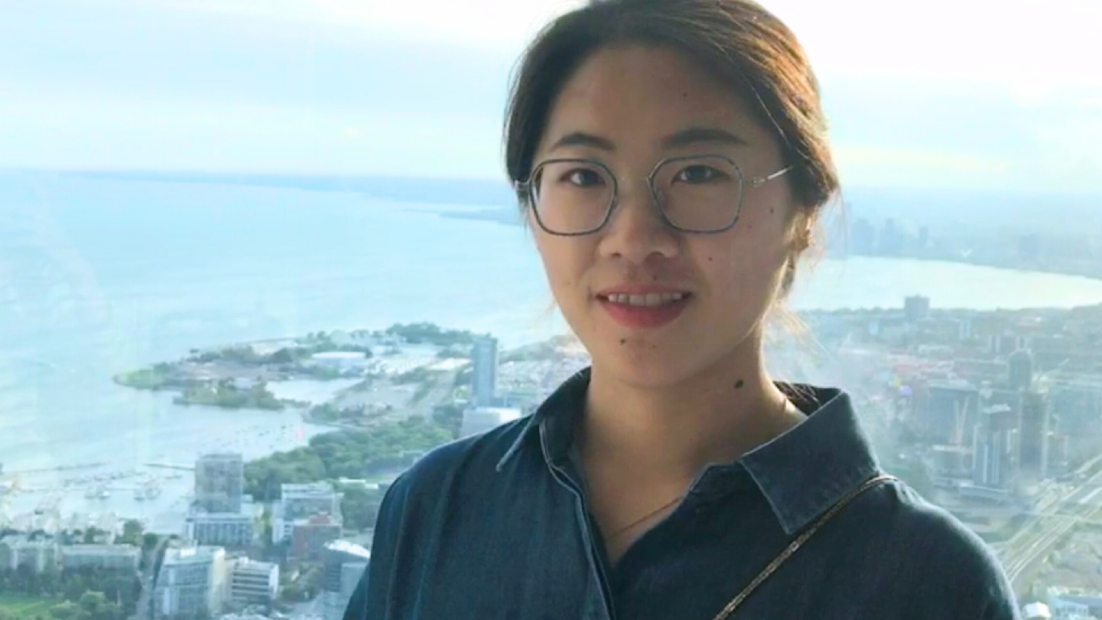 student standing in front of a city skyline along a shore.