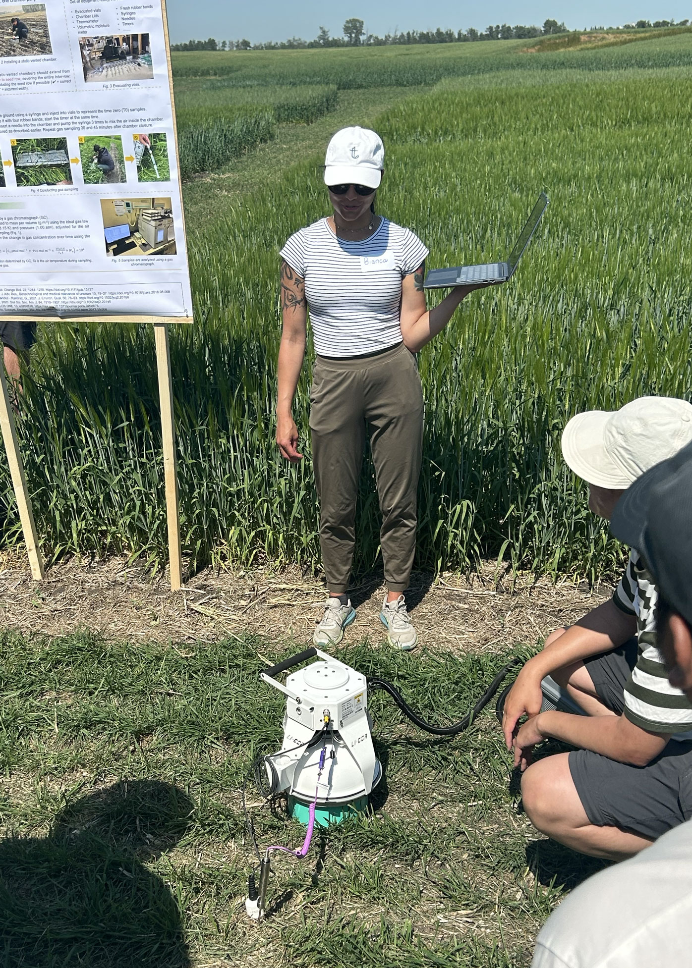 Photo taken out in a field where a student is demonstrating a small machine that measures elements in the air