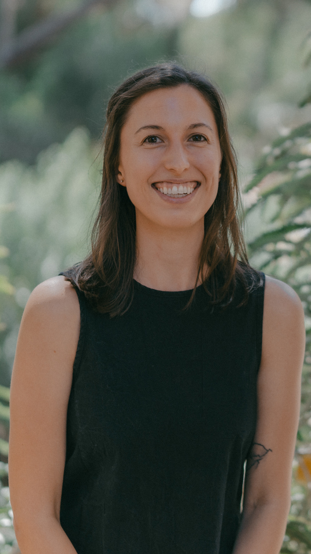 Closeup photo of a smiling Claire with a lush forest backdrop behind her