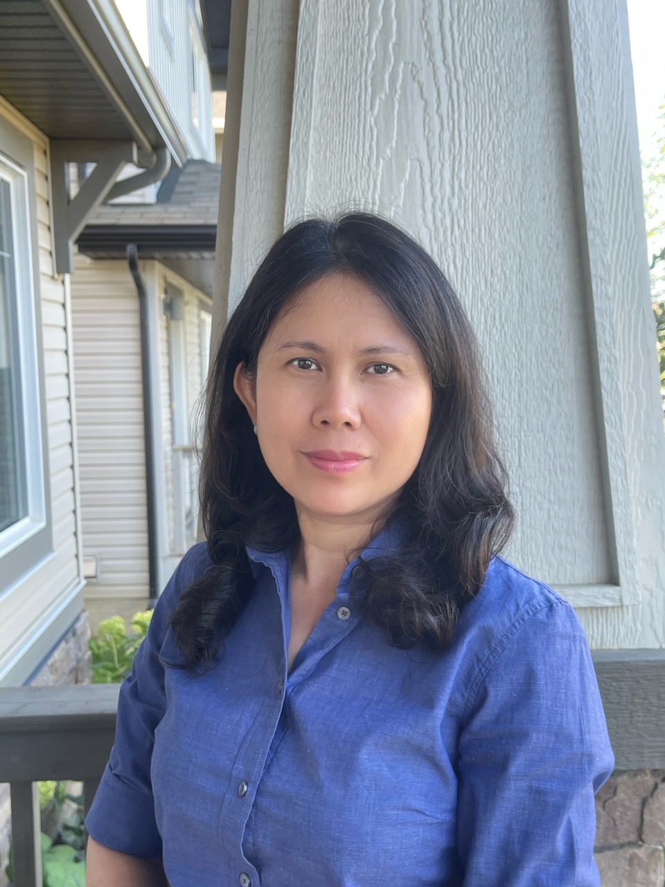 Duyen poses with a kind smile outside on a front porch