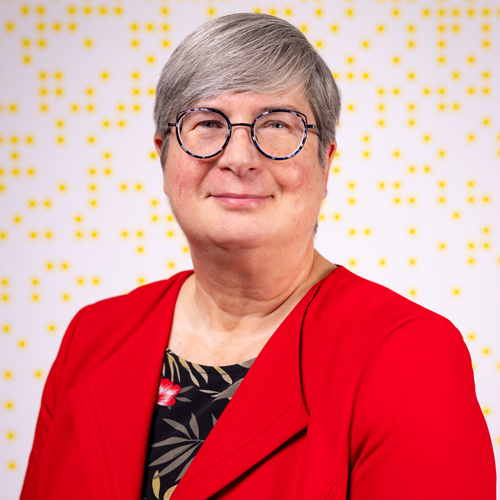 Heather wears a statement red blazer in a professional headshot