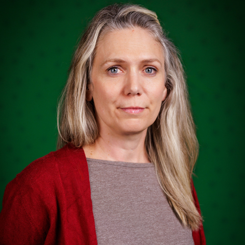 Justine poses inside in front of a U of A green backdrop