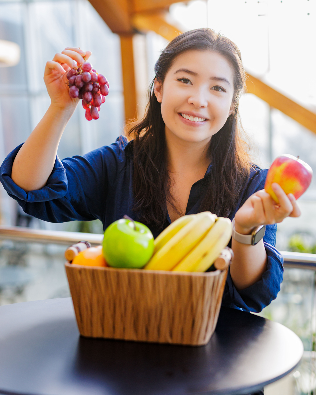 A current student poses in the ALES atrium with a basket of fruit