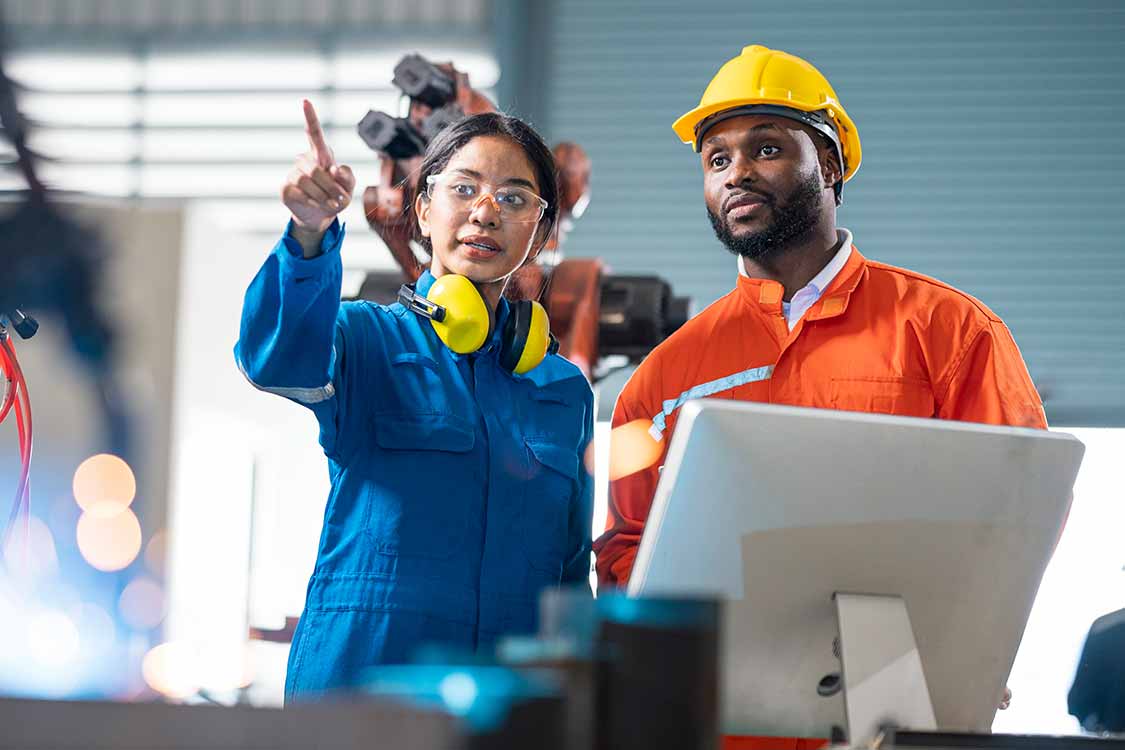 Two engineers with safety equipment work on a project