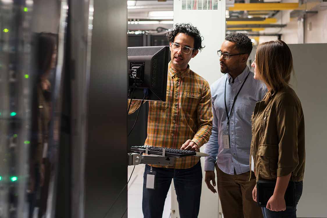 Group of engineers discuss in front of servers