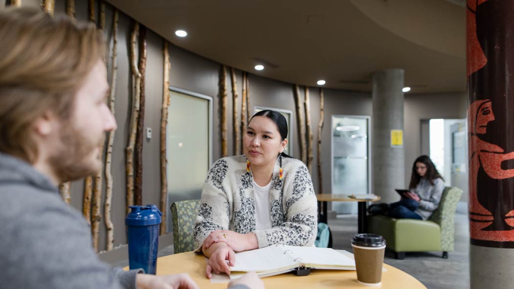 Indigenous students working at a table in Wahkohtowin Lodge