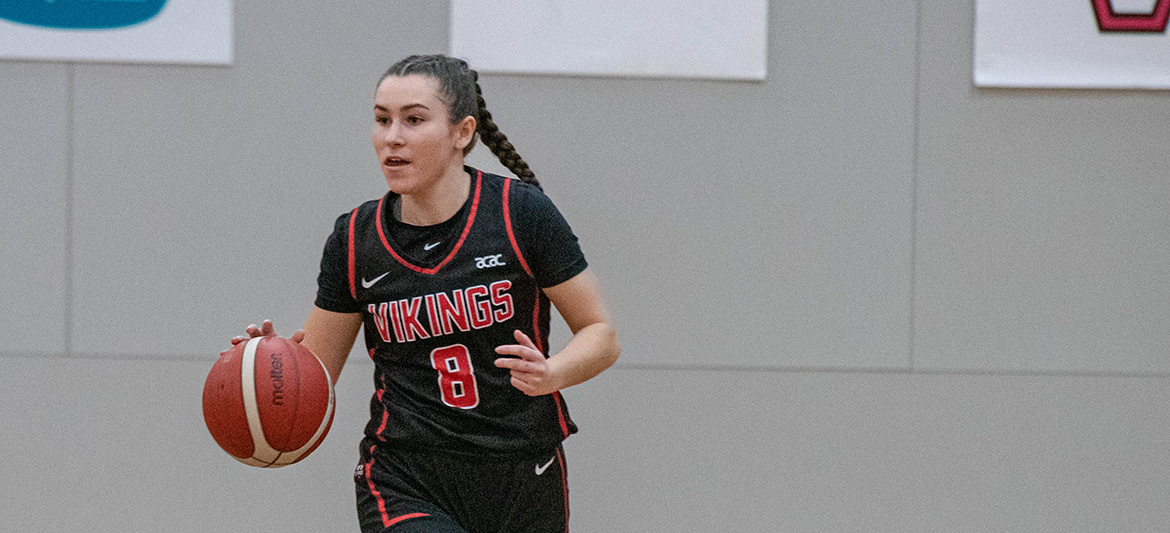 A Vikings women's basketball team member dribbling a basketball.