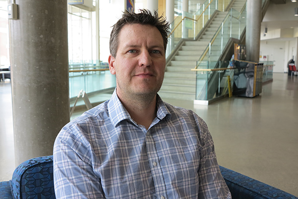 A photo of Clark Banack in a blue plaid shirt in the Augustana forum.