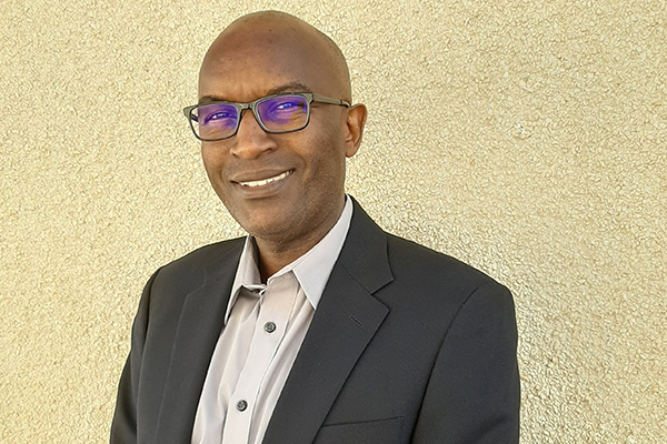 A photo of James Kariuki wearing a suit in front of a pale background.