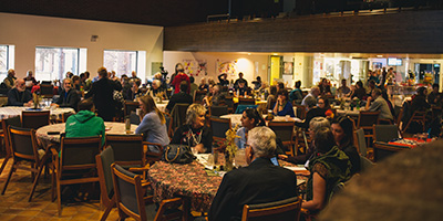 A photo of a large room of people sitting around conference tables