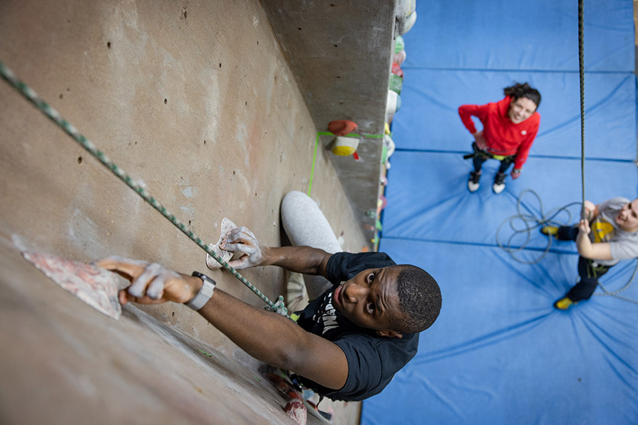 A student climbing up the climbing wall.