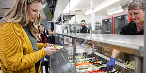 A student deciding on what food to choose in the dining hall.