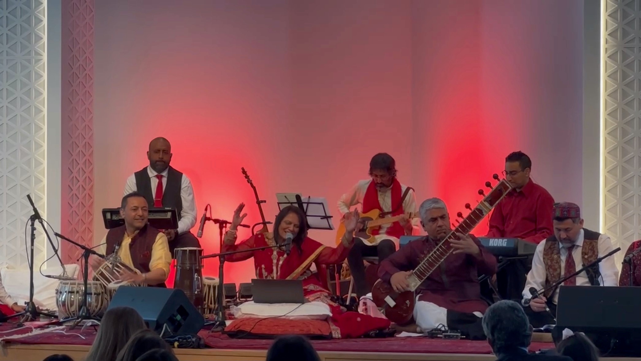 Seated musicians performing with red background