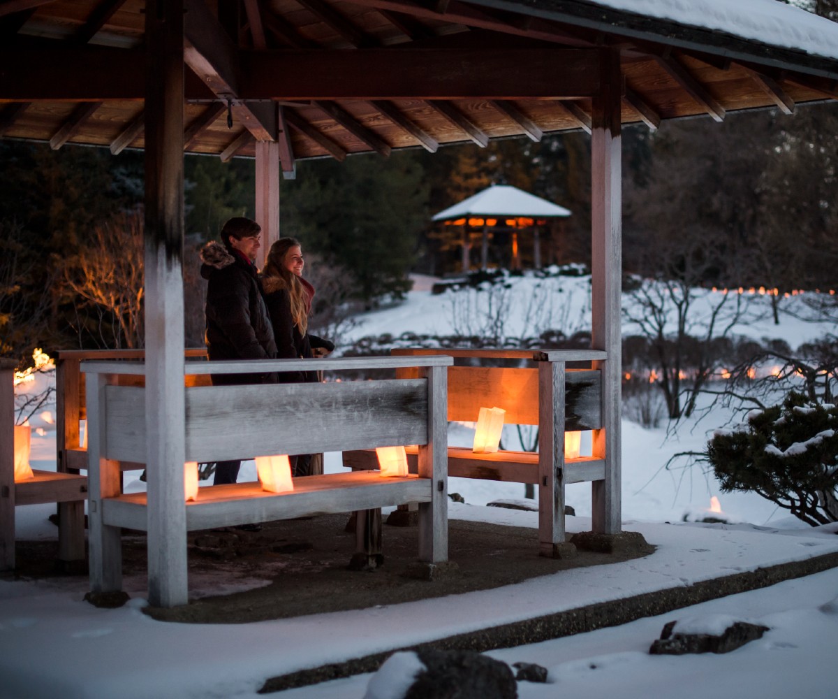 2 people on winter landscape looking at paper lanterns at Luminaria