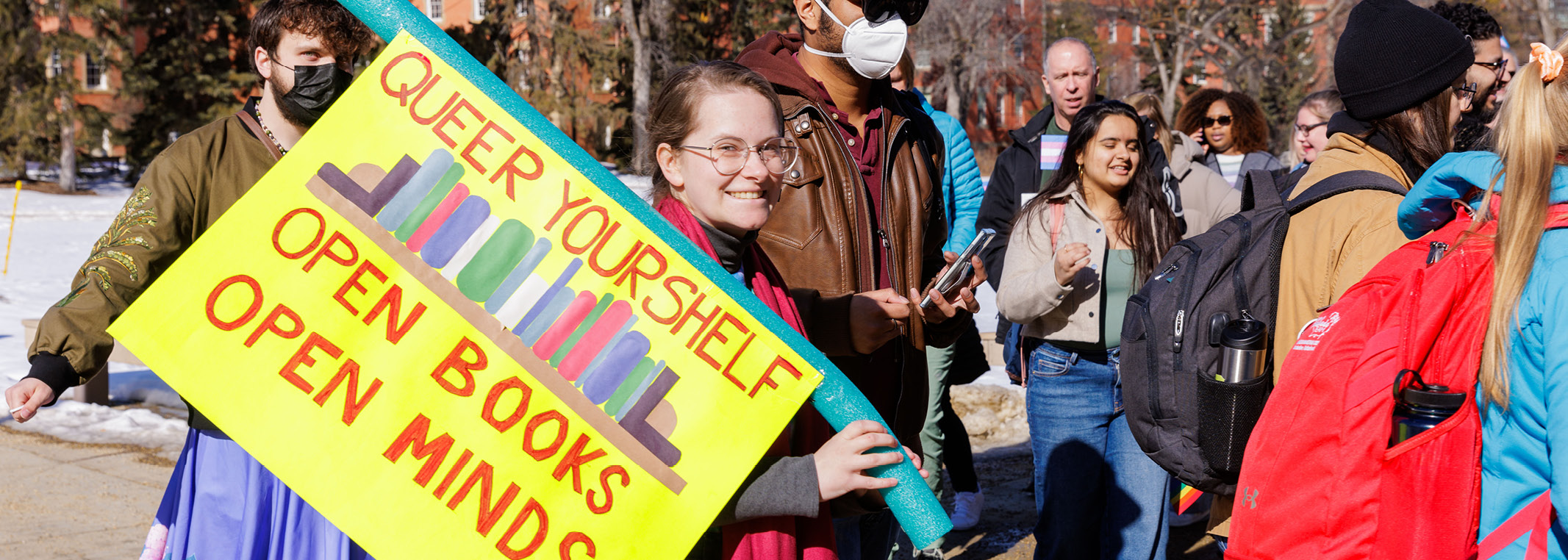 Woman holding sign that says Queer yourself open books open minds