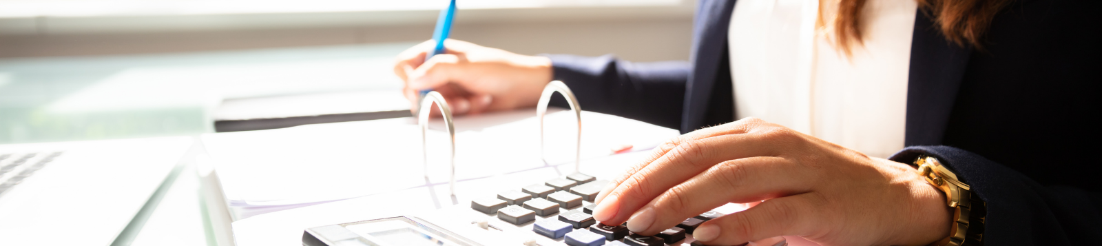 Picture of a person at a desk doing calculations with a calculator