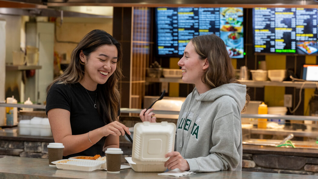 Two women eating take out in cafateria