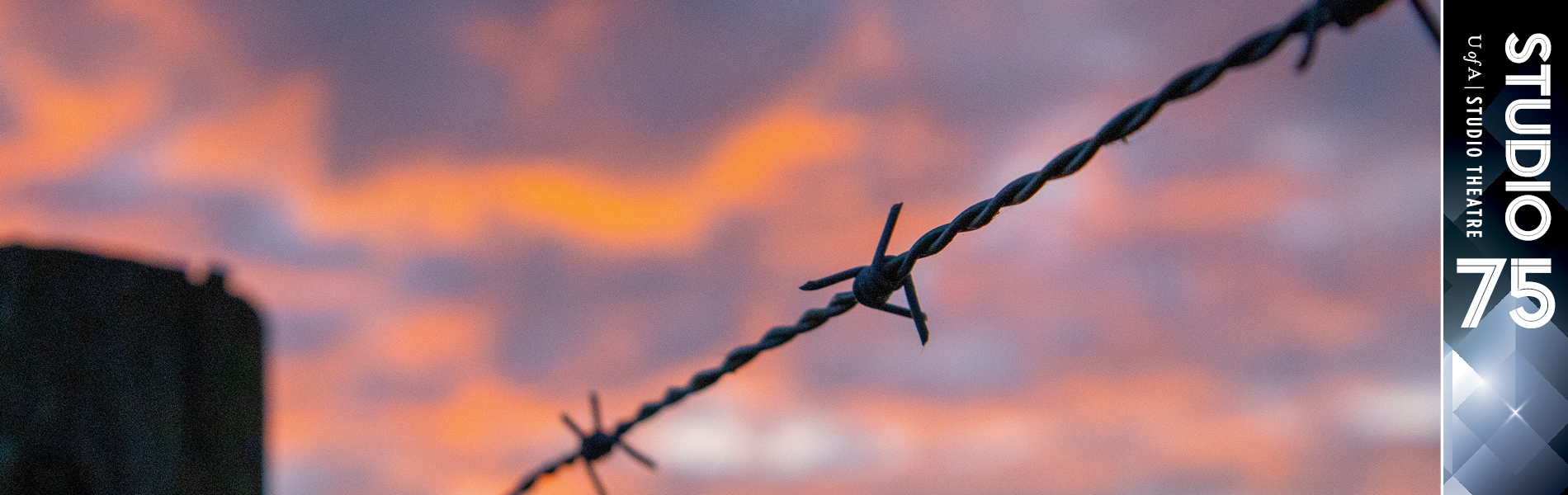 A barbed wire fence against the sky. The sky cloudy with sunset shades of purple, blue and orange.