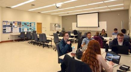 Students work together at grouped tables in the urban planning design studio