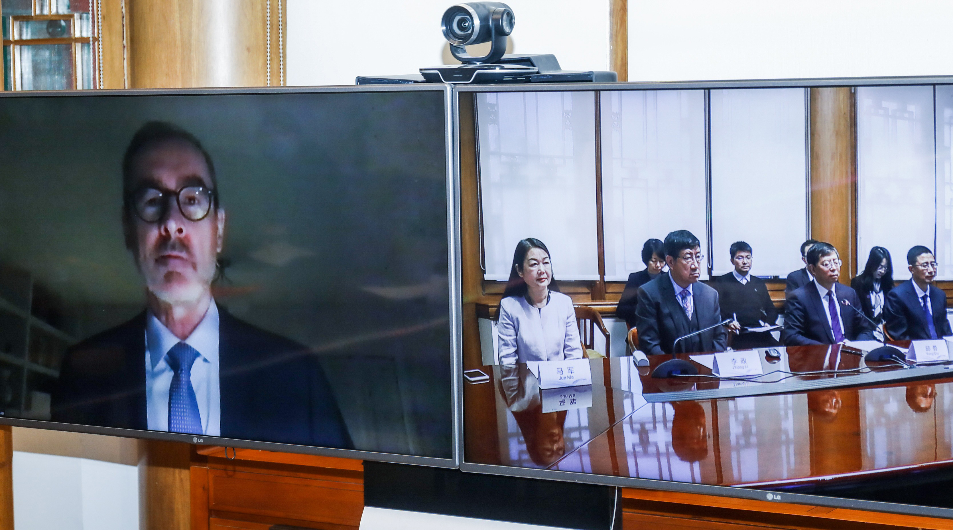 University of Alberta President Bill Flanagan on one screen (left) and attendees of the Global Energy Research Partnership renewal meeting on another screen (right)