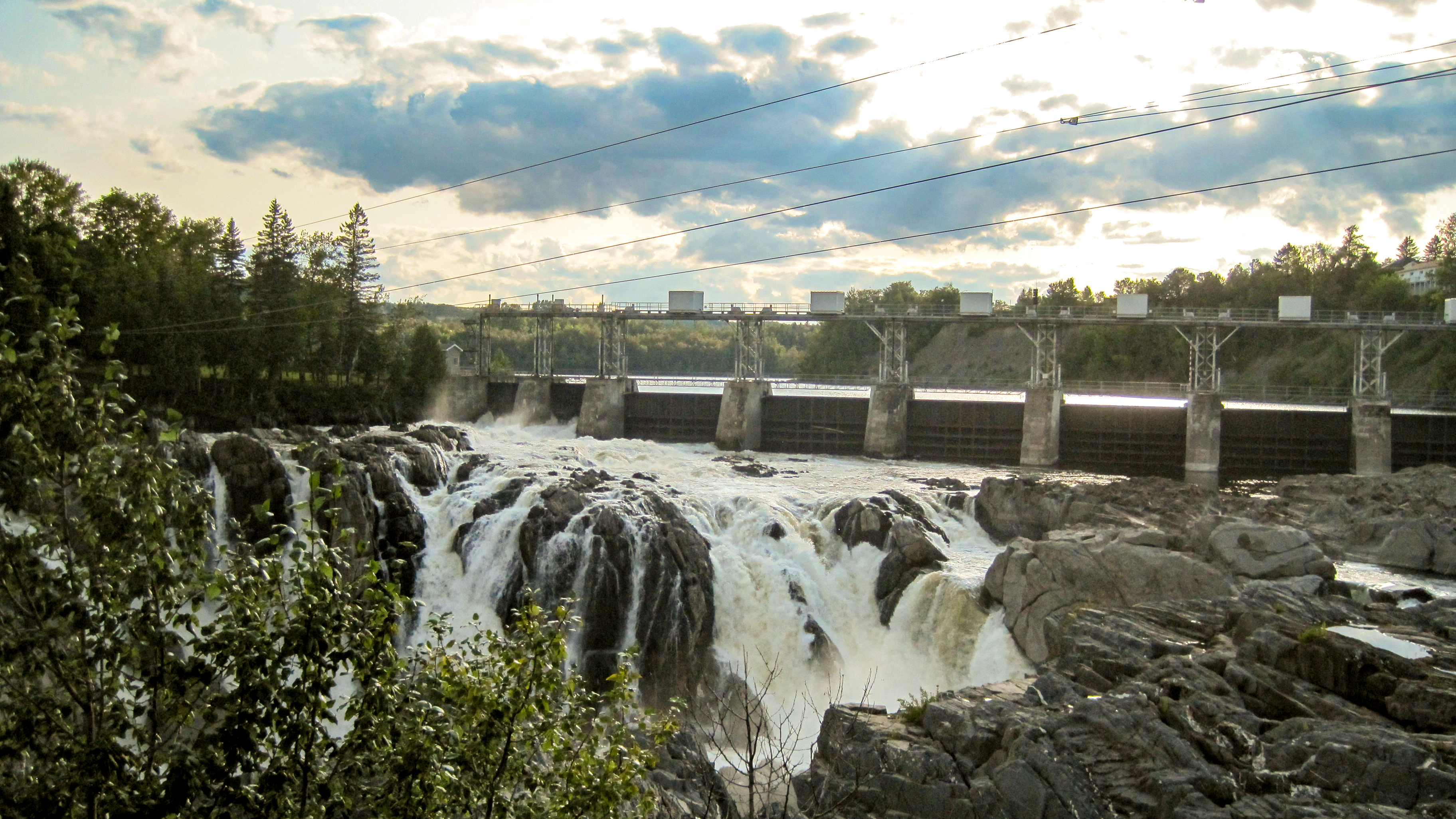 A dam with water flowing over rocks in front