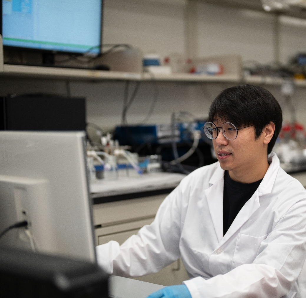 student at computer working in lab with labcoat on