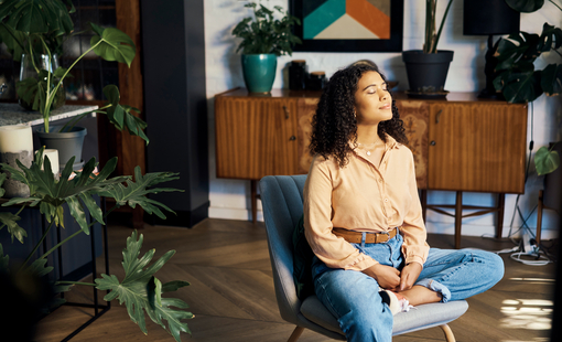 Woman sitting in chair in room with plants.