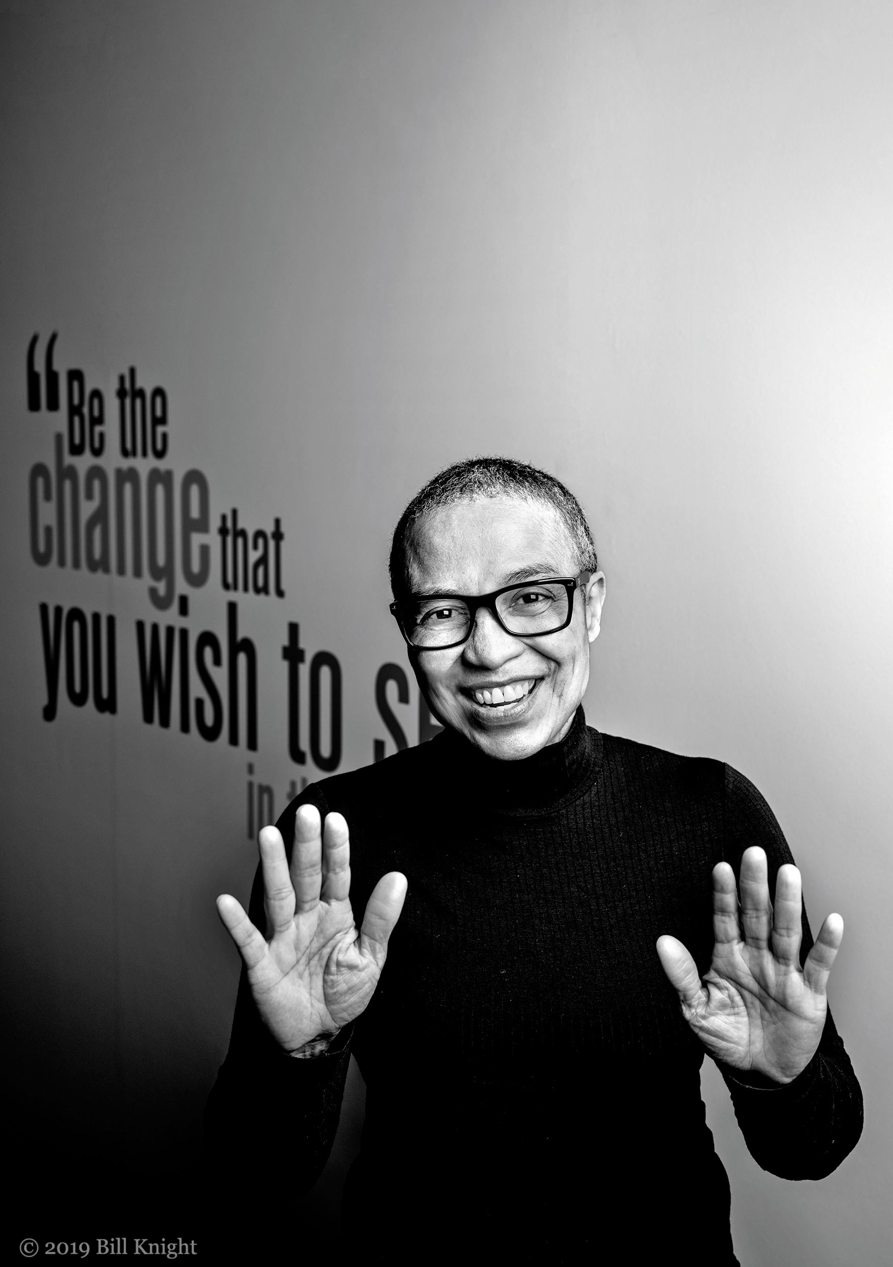 Shirley Anne Tate standing in front of a mural that read "Be the change that you wish to see in the world"