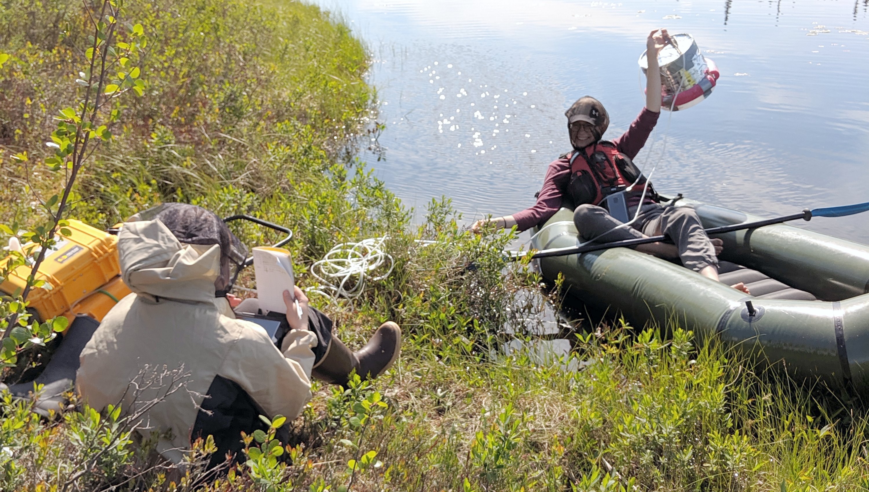 Researcher McKenzie Kuhn (right) and field assistant Maya Frederickson measure methane emissions from a lake using a floating chamber and a portable greenhouse gas analyzer. (Photo: Lauren Thompson)