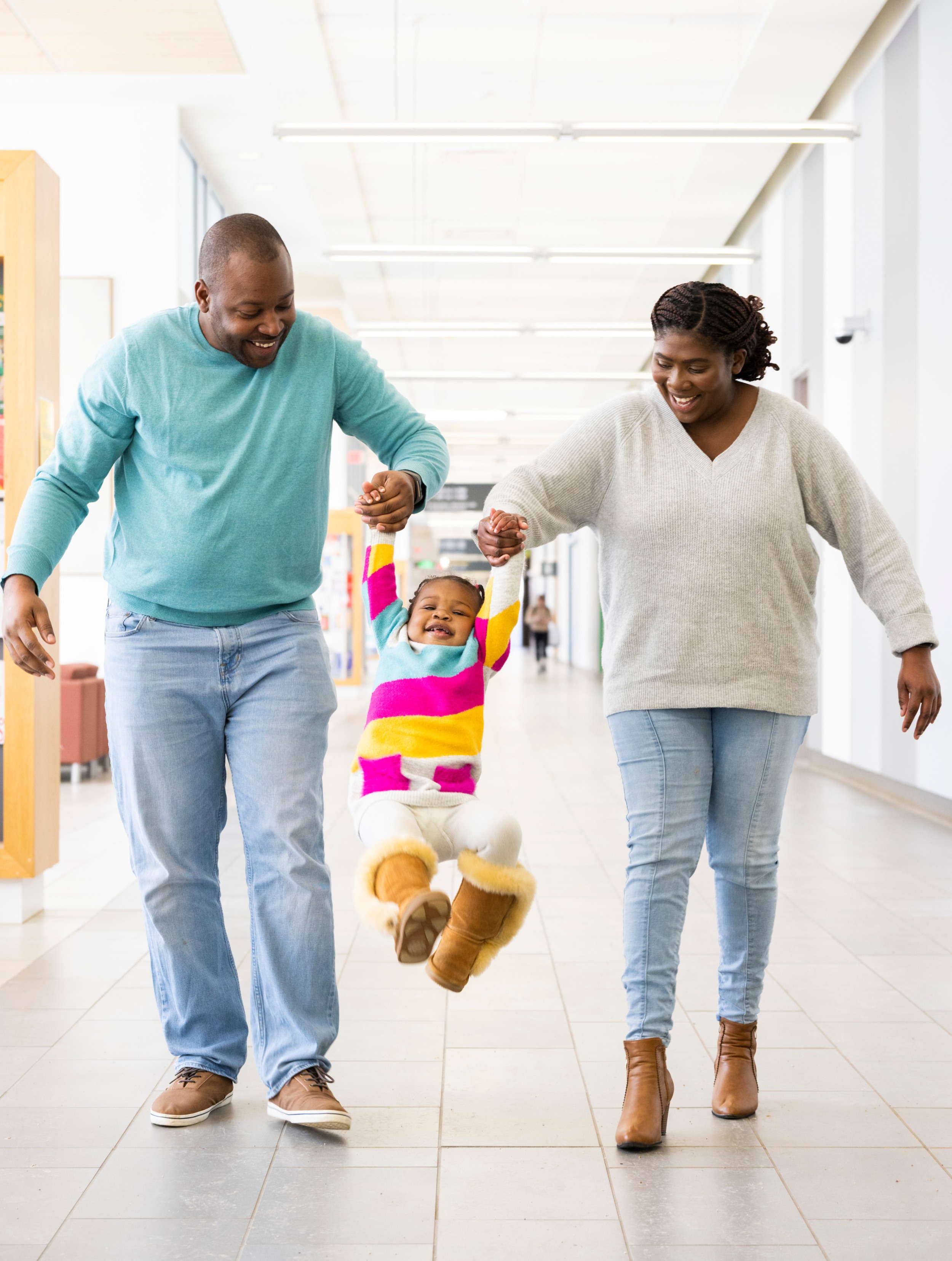 Nursing master's grad Jodi-Ann Robinson-Perry (right) and her husband Dushane swing their 19-month-old daughter Payton as they take a stroll in the Edmonton Clinic Health Academy. (Photo: John Ulan) 