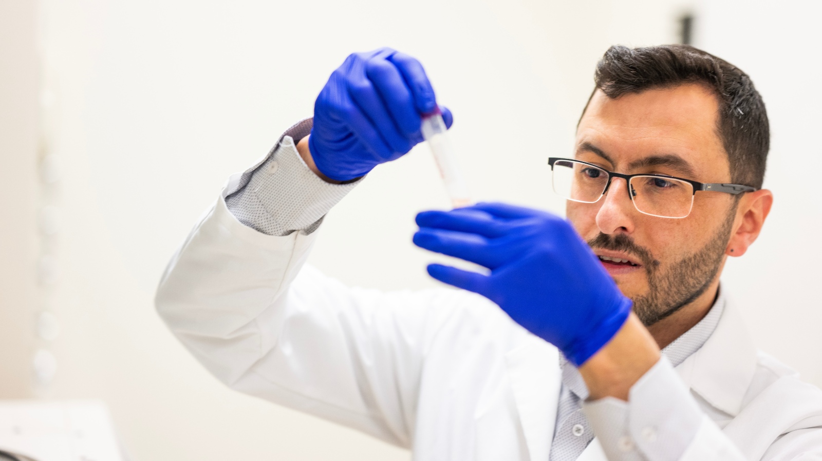 PhD grad Yasser Tabana examining a liquid in a lab