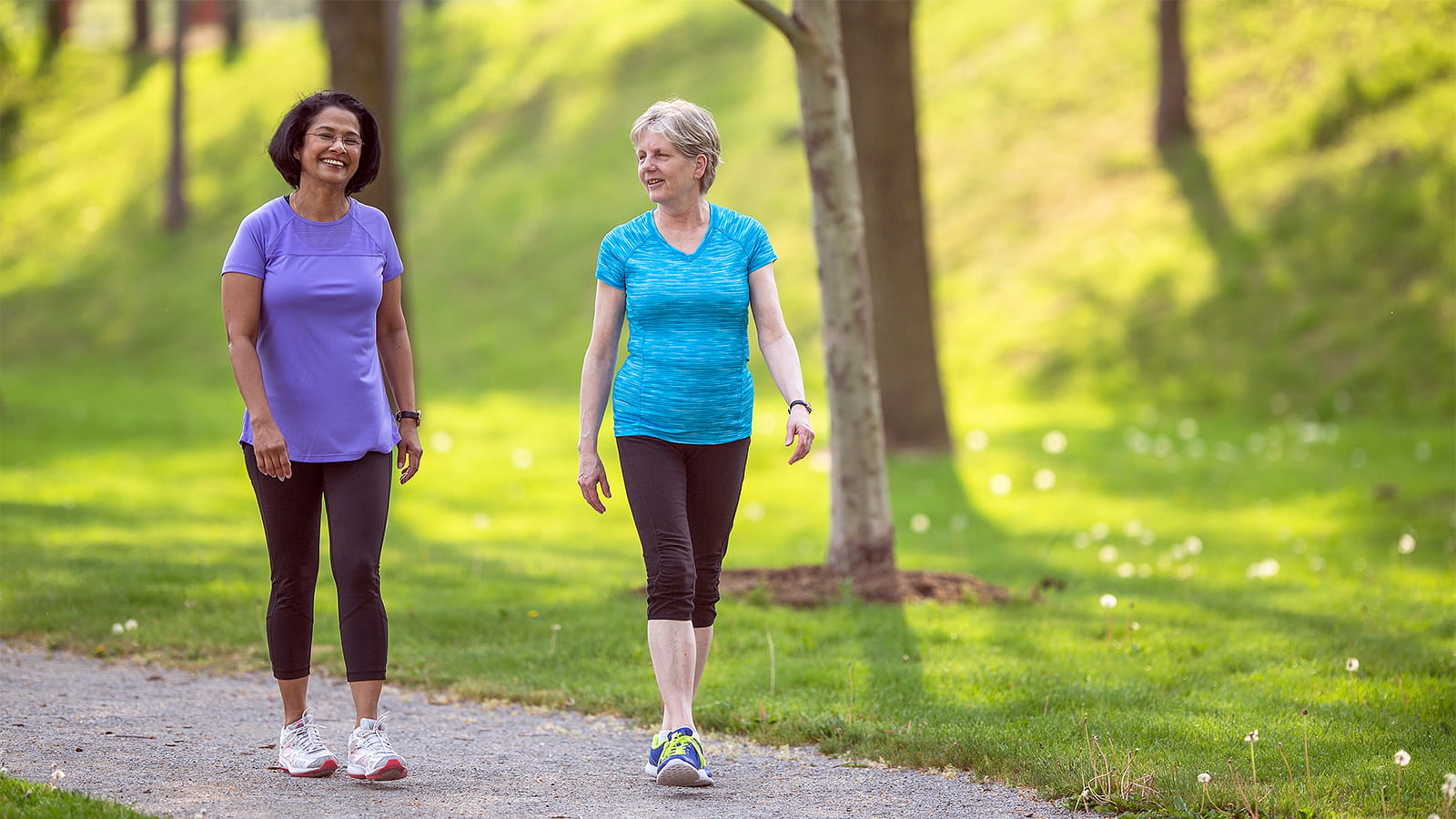 Two women walk on a path outdoors. (Photo: Getty Images)