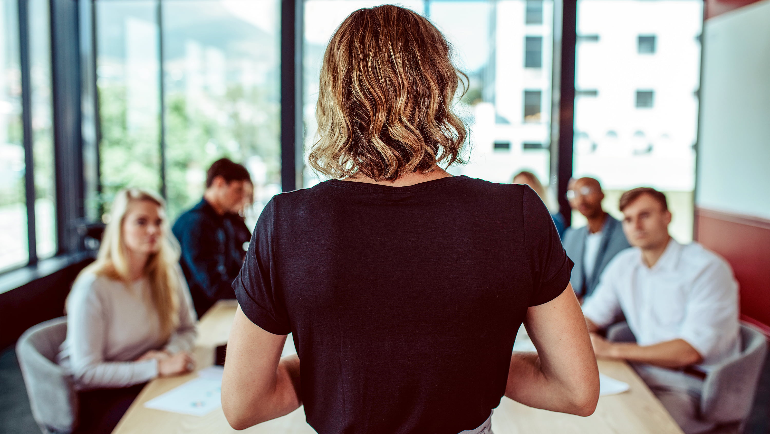 Woman presents to board room full of employees. (Photo: Getty Images)