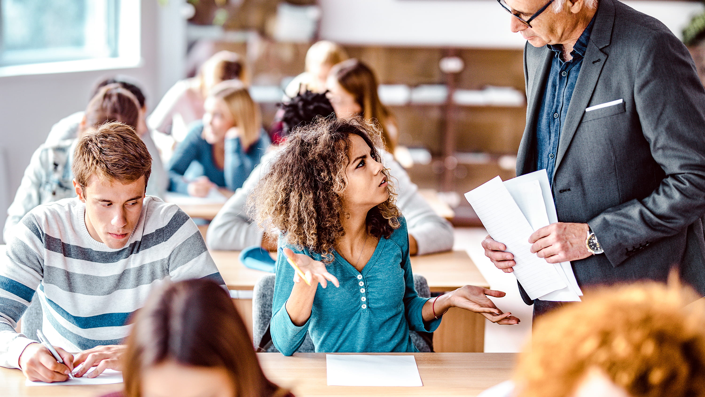 An upset student speaks with a teacher in a classroom. (Photo: Getty Images)