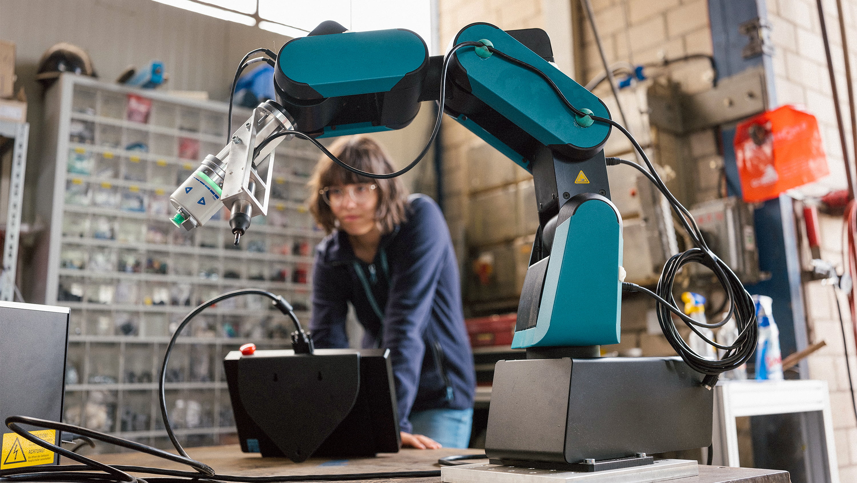 Female technician programs a robot arm with a digital tablet. (Photo: Getty Images)