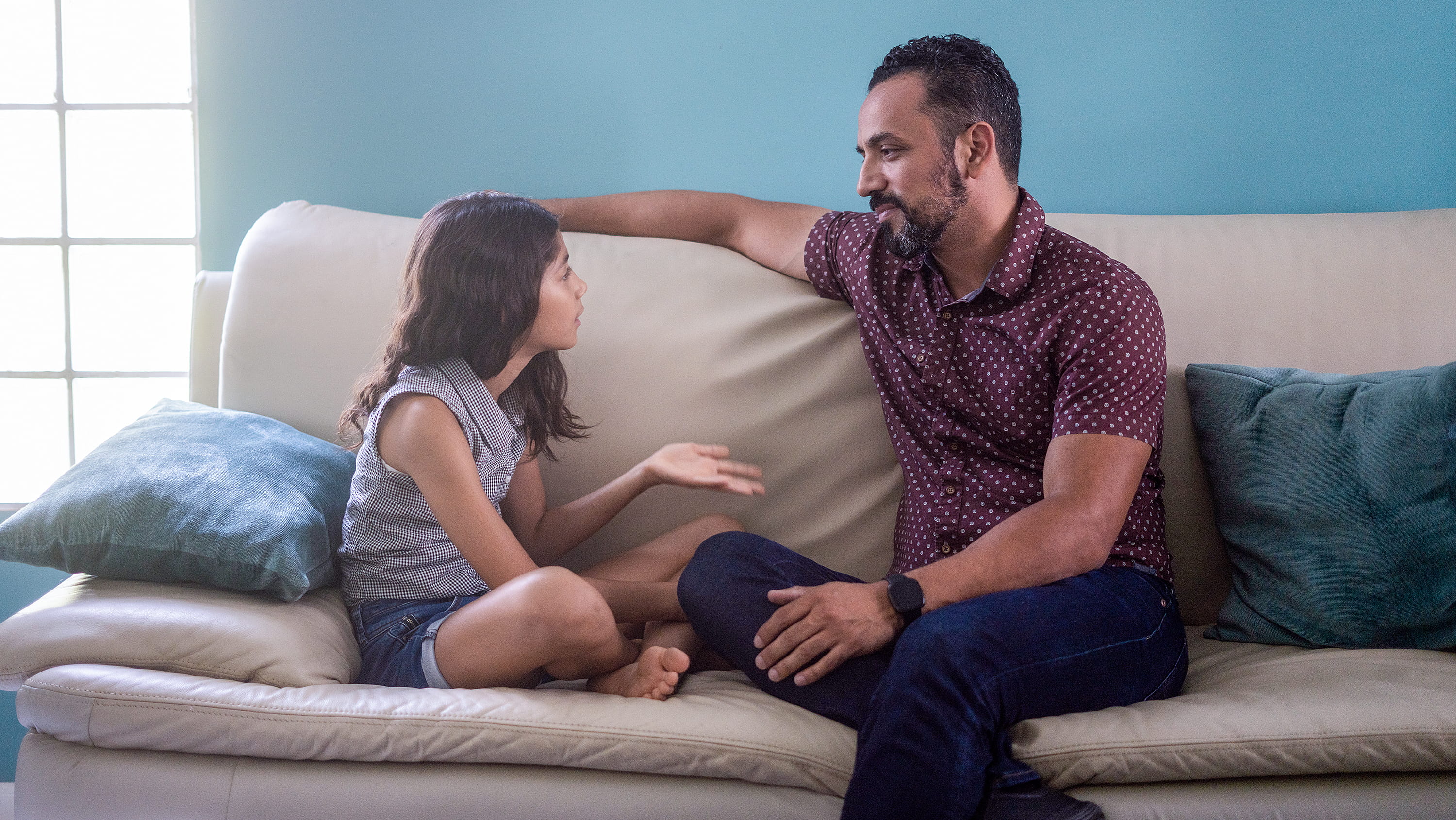 Father and daughter sit on sofa talking. (Photo: Getty Images)