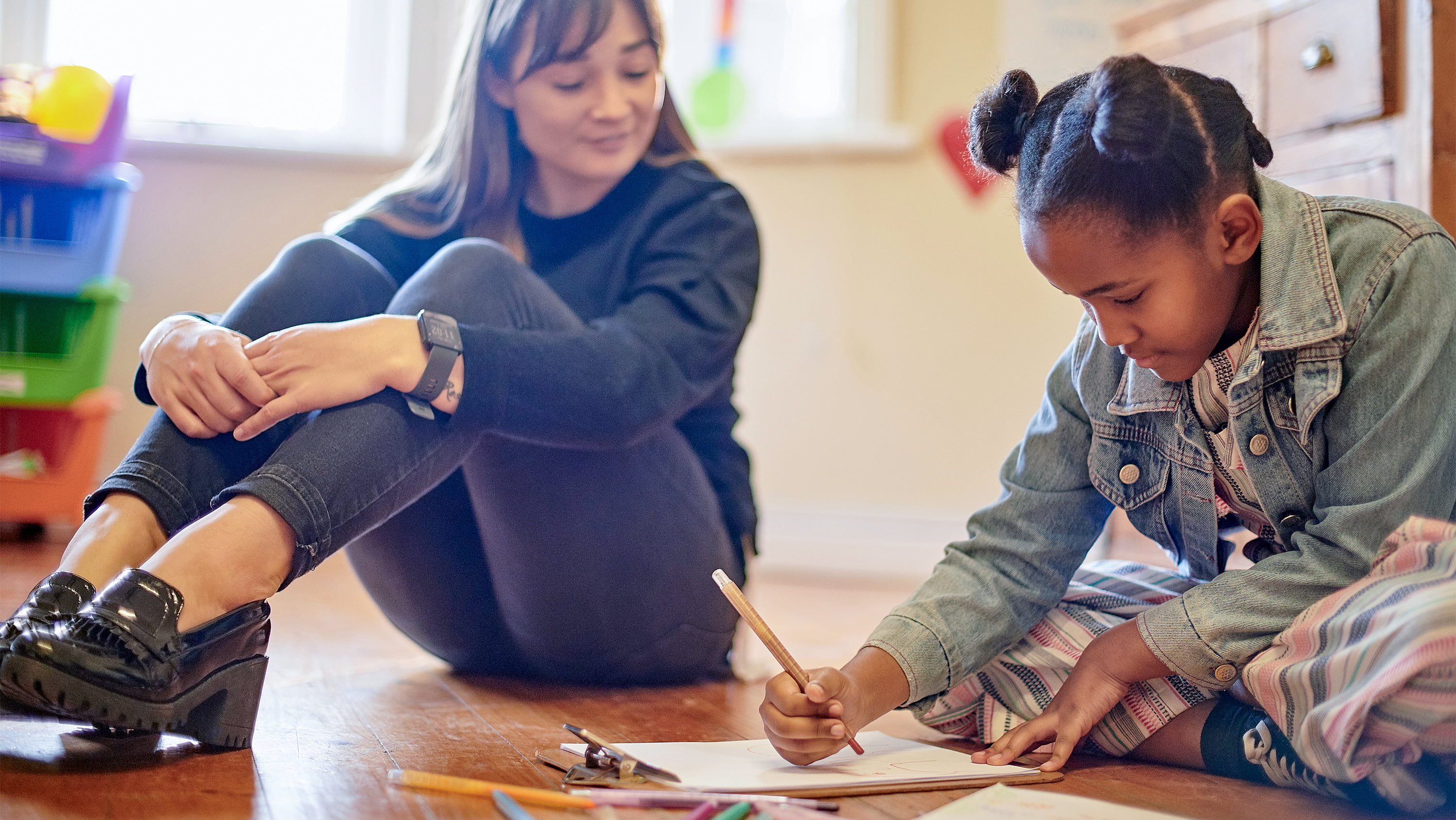 Young student draws a picture while a teacher sits nearby watching. (Photo: Getty Images)