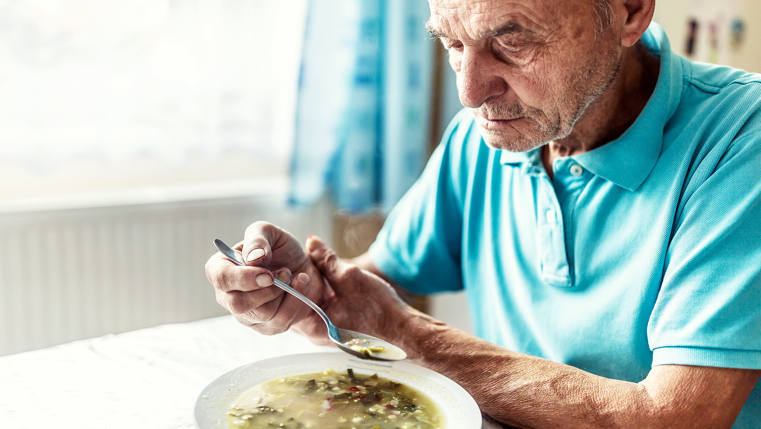 Man with Parkinson's disease eats a bowl of soup. (Photo: Getty Images)